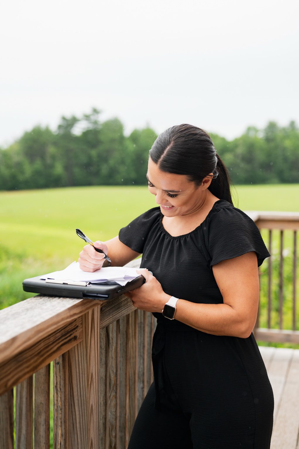 Kayla reviewing wedding planning notes on a clipboard outdoors at Lost Valley