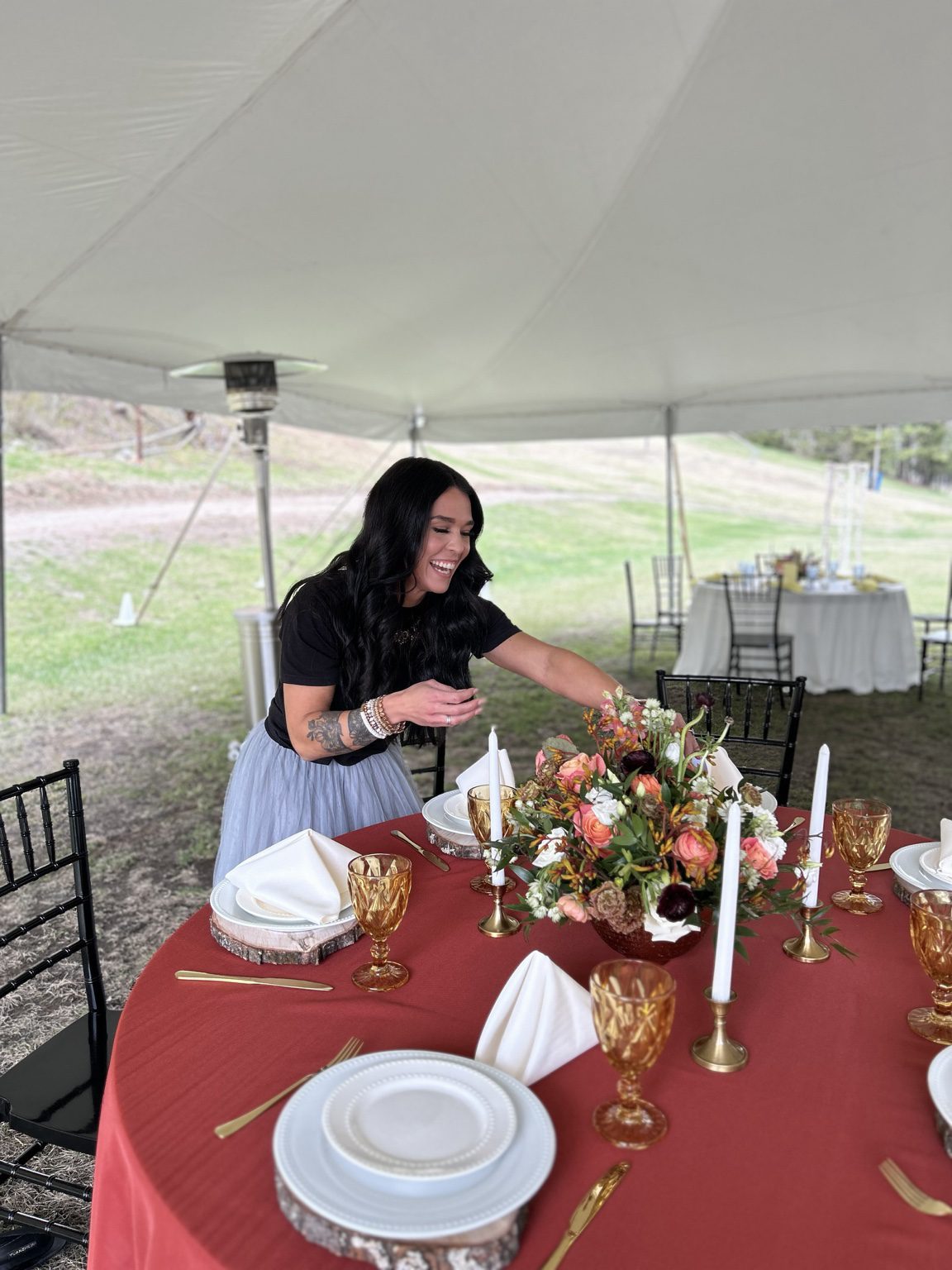 Kayla arranging flowers and table settings for a wedding reception at Lost Valley